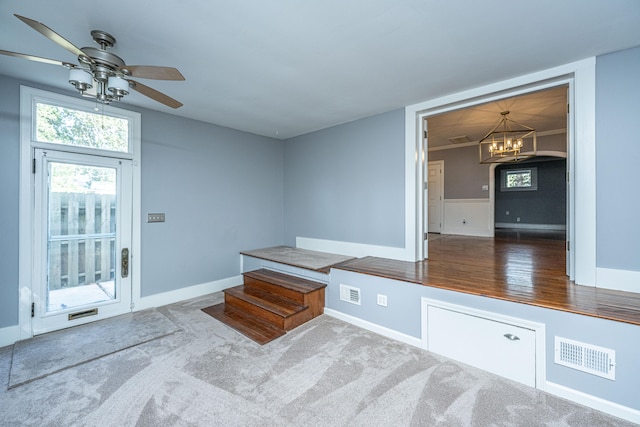 interior space with carpet and ceiling fan with notable chandelier