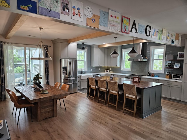 1495 Keshi Pearl Dr, Mount Pleasant, SC 29466 - kitchen with stainless steel fridge with ice dispenser, a sink, wall chimney range hood, tasteful backsplash, and wood finished floors