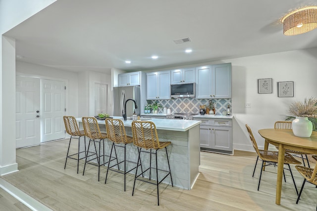 169 Southwold Cir, Goose Creek, SC 29445 - kitchen featuring stainless steel appliances, light countertops, a center island with sink, backsplash, and light wood-style floors