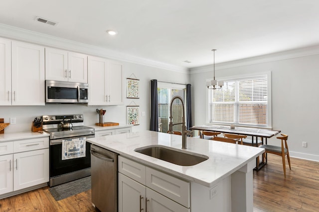 kitchen with stainless steel appliances, a sink, visible vents, dark wood-style floors, and crown molding