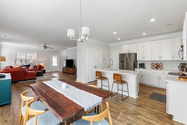 dining space with crown molding, recessed lighting, visible vents, wood finished floors, and ceiling fan with notable chandelier