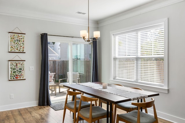 dining space featuring a notable chandelier, baseboards, crown molding, and wood finished floors