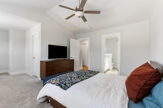 bedroom featuring light carpet, baseboards, a ceiling fan, ensuite bath, and vaulted ceiling