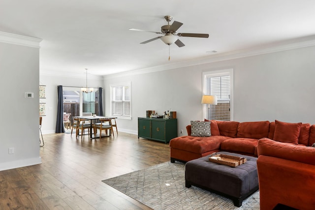 living area with ornamental molding, ceiling fan with notable chandelier, visible vents, and wood finished floors