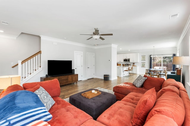 living room featuring visible vents, crown molding, and wood finished floors