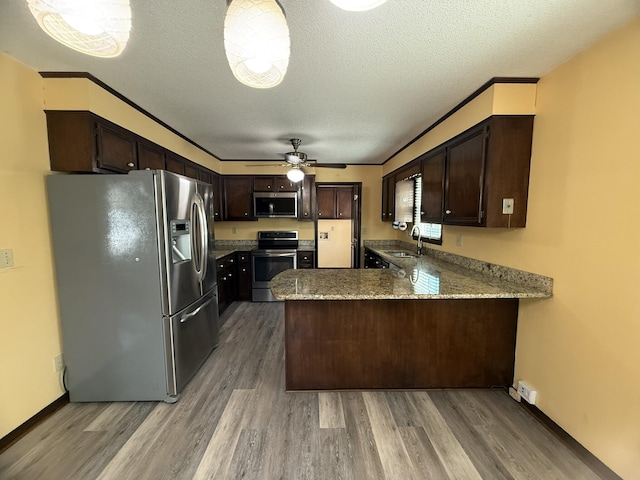 kitchen featuring a peninsula, dark brown cabinetry, stainless steel appliances, and wood finished floors