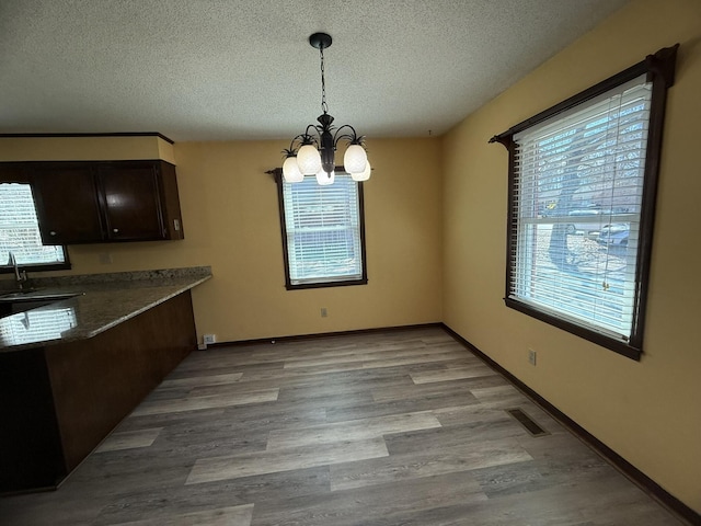 unfurnished dining area featuring plenty of natural light, visible vents, a notable chandelier, and a textured ceiling