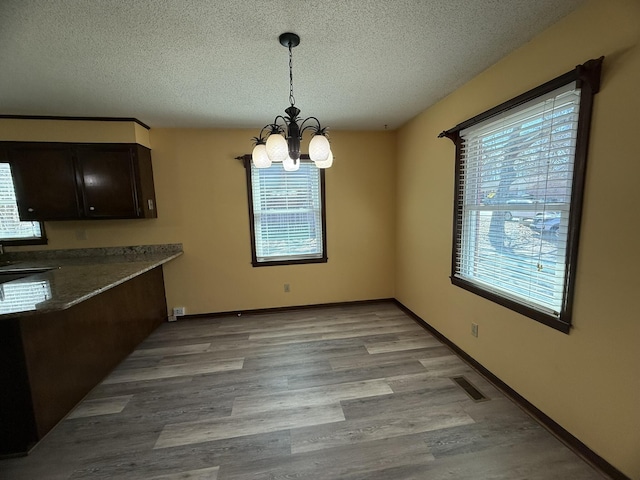 unfurnished dining area featuring a healthy amount of sunlight, visible vents, and a notable chandelier