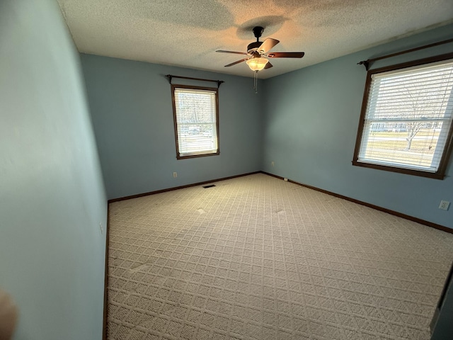 empty room featuring visible vents, baseboards, a ceiling fan, a textured ceiling, and carpet flooring