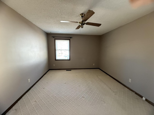 spare room with ceiling fan, baseboards, and a textured ceiling