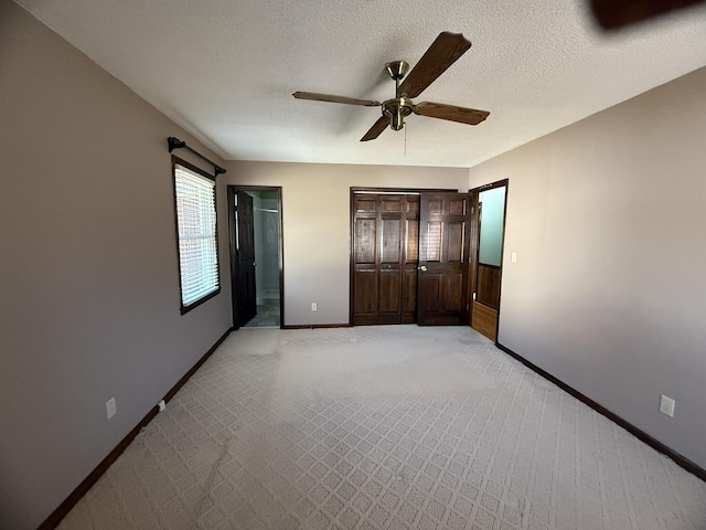 unfurnished bedroom featuring a textured ceiling, ceiling fan, light carpet, and baseboards