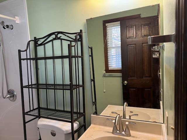 bathroom featuring a shower, vanity, and toilet