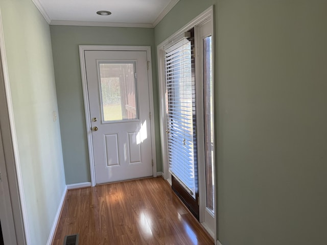 doorway to outside featuring visible vents, crown molding, baseboards, and wood finished floors