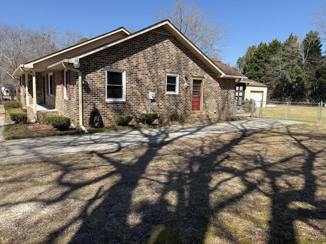 view of property exterior with brick siding, an attached garage, and fence