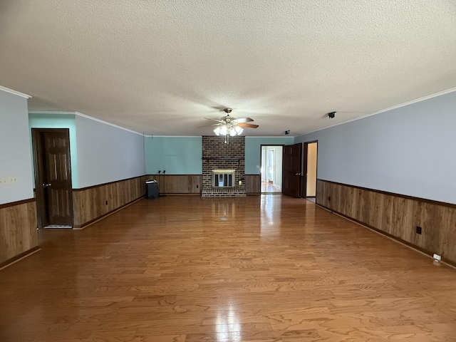 unfurnished living room with a ceiling fan, wainscoting, and wooden walls