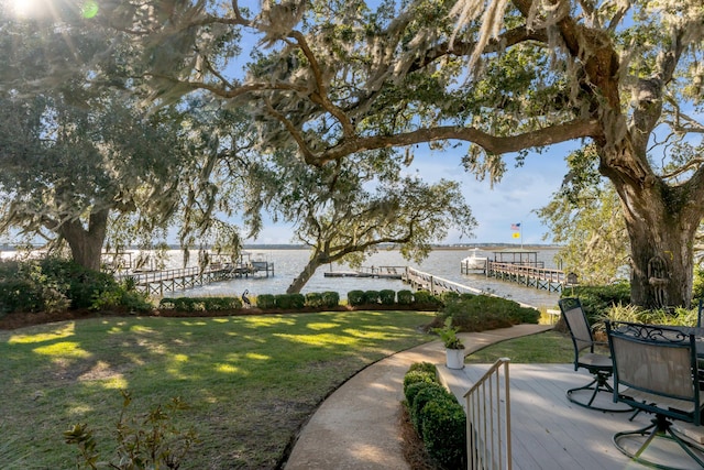 exterior space featuring a water view, a dock, and a lawn