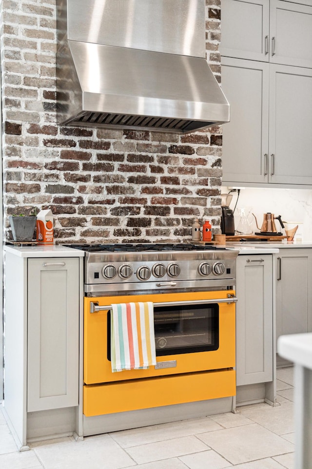 11 Franklin St, Charleston, SC 29401 - kitchen featuring high end stainless steel range oven, wall chimney range hood, light tile patterned floors, and light countertops