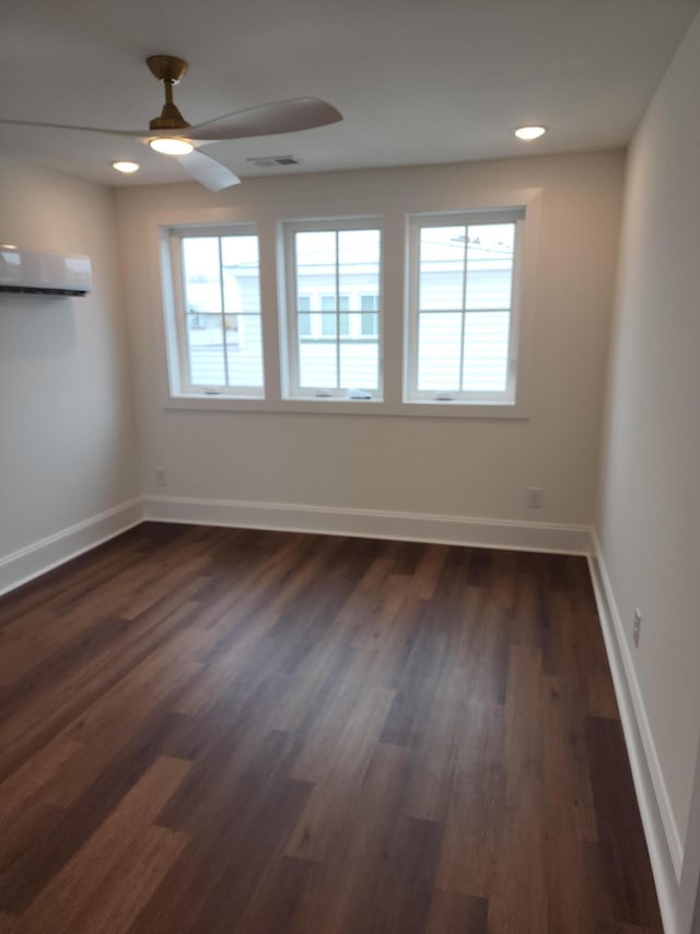 unfurnished room featuring dark wood-type flooring, an AC wall unit, and ceiling fan