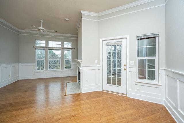 unfurnished living room featuring ceiling fan, light wood-type flooring, and ornamental molding