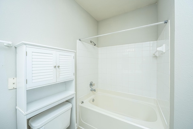 bathroom featuring tiled shower / bath combo and toilet