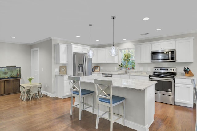 kitchen with a center island, dark hardwood / wood-style floors, appliances with stainless steel finishes, decorative light fixtures, and white cabinetry