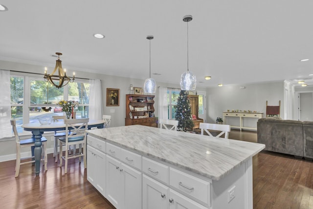 kitchen with light stone counters, pendant lighting, white cabinets, a center island, and dark hardwood / wood-style floors