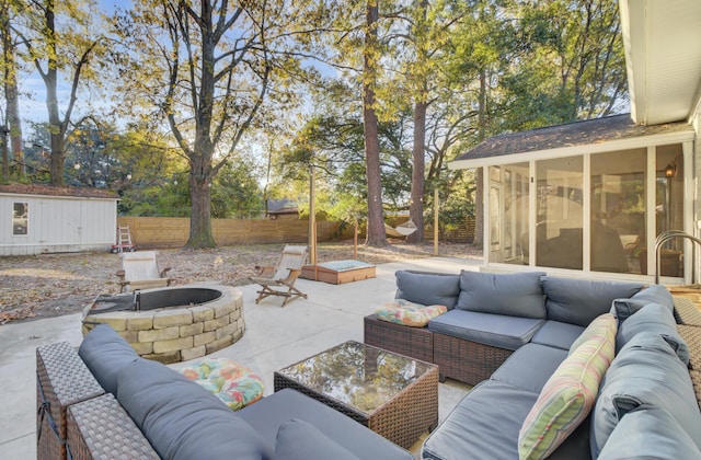 view of patio featuring a sunroom, a shed, and an outdoor living space with a fire pit