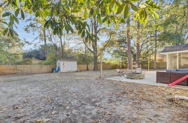 view of yard with a patio area, a storage unit, and an outdoor fire pit