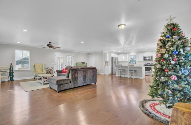 living room with hardwood / wood-style floors, ceiling fan, and ornamental molding