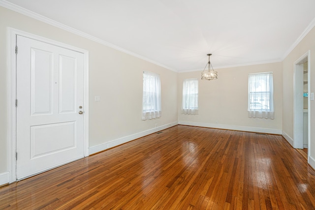 spare room with baseboards, ornamental molding, dark wood finished floors, and a notable chandelier