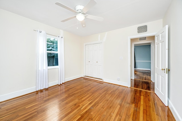 unfurnished bedroom with hardwood / wood-style flooring, visible vents, baseboards, and a closet