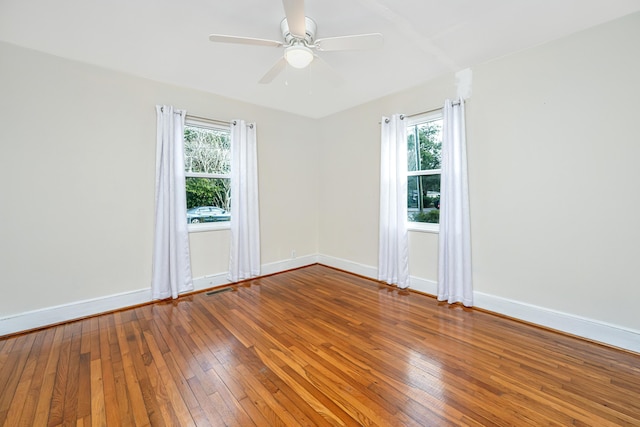 empty room featuring ceiling fan, wood-type flooring, visible vents, and baseboards