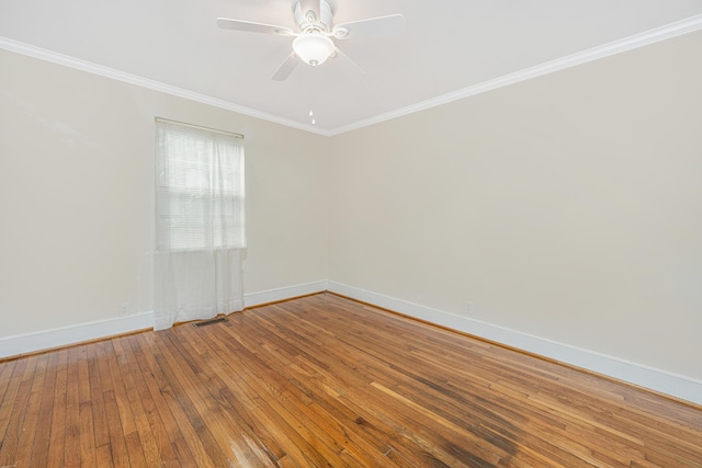 spare room featuring visible vents, baseboards, a ceiling fan, wood-type flooring, and crown molding