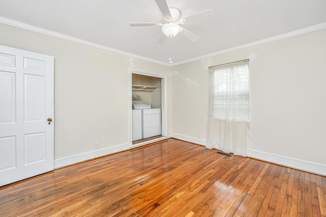 empty room with baseboards, ornamental molding, wood-type flooring, and washer and dryer