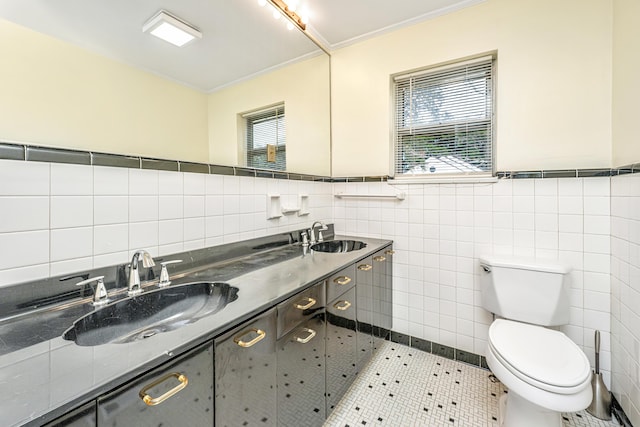 bathroom with toilet, crown molding, tile walls, and a sink