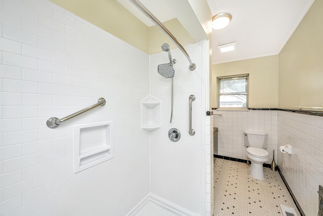 full bathroom featuring wainscoting, toilet, ornamental molding, a shower stall, and tile walls