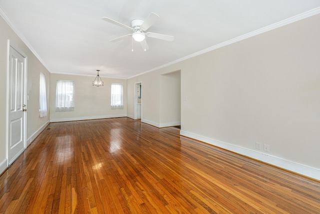 spare room featuring wood-type flooring, ceiling fan with notable chandelier, baseboards, and ornamental molding