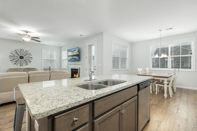 kitchen with pendant lighting, dishwasher, sink, ceiling fan with notable chandelier, and light hardwood / wood-style flooring