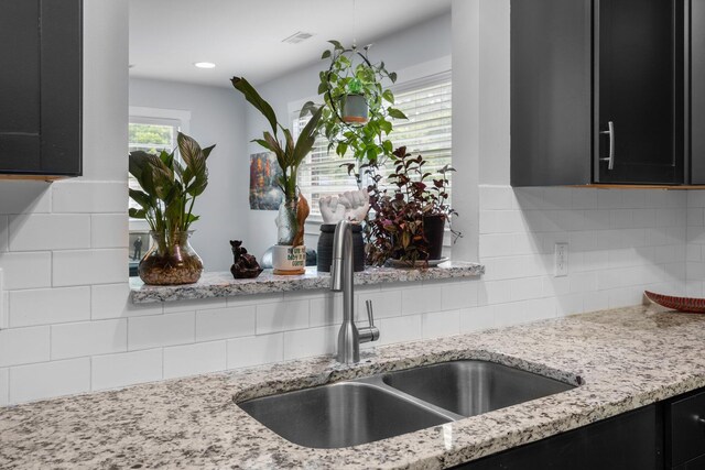 2651 Martha Dr, North Charleston, SC 29405 - kitchen view of a sink, dark cabinets, decorative backsplash, and light stone countertops