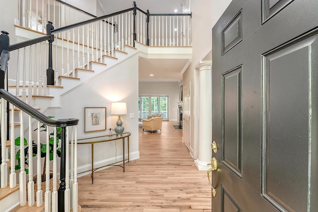 foyer featuring crown molding, baseboards, wood finished floors, and stairs