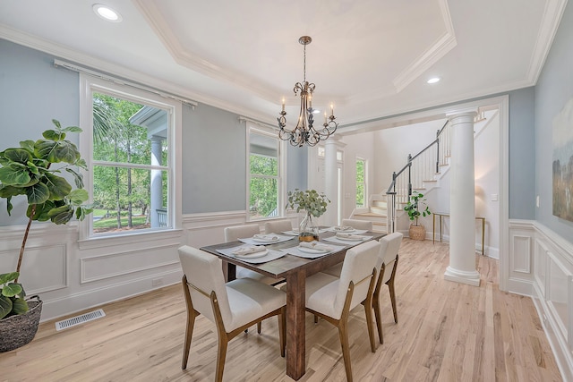dining area with visible vents, a notable chandelier, a decorative wall, crown molding, and light wood finished floors