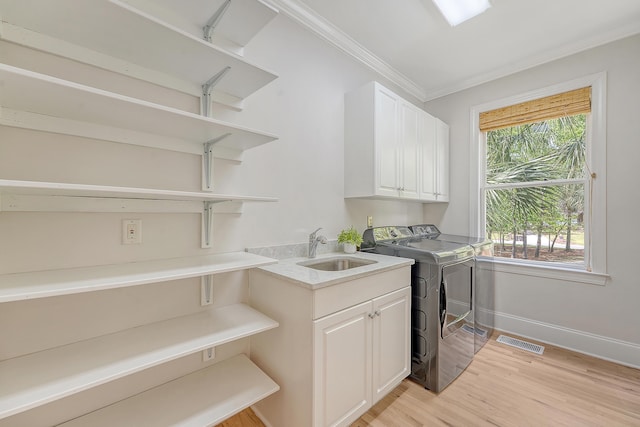 laundry room featuring separate washer and dryer, ornamental molding, visible vents, cabinet space, and light wood finished floors