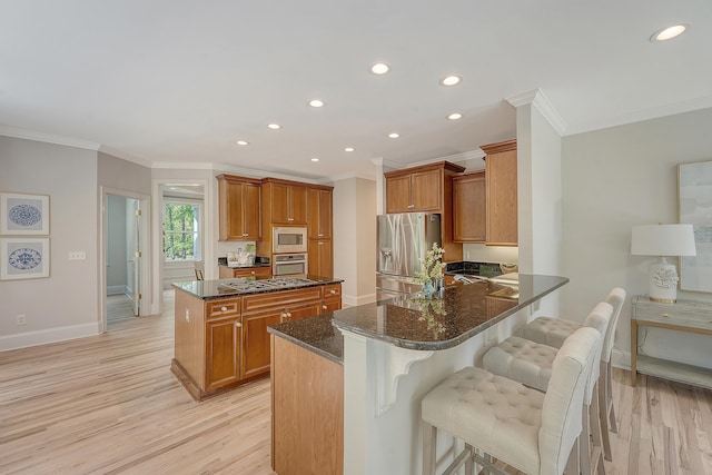 kitchen featuring brown cabinets, dark stone counters, ornamental molding, and stainless steel appliances
