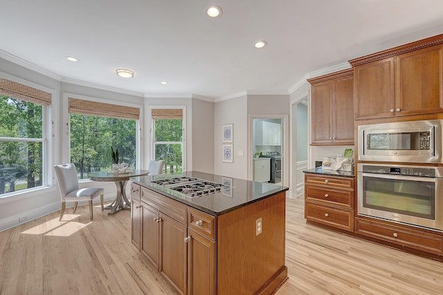kitchen featuring light wood-style floors, crown molding, independent washer and dryer, a center island, and stainless steel appliances