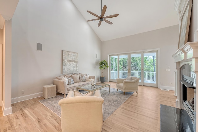 living area featuring a fireplace with flush hearth, high vaulted ceiling, ceiling fan, and baseboards