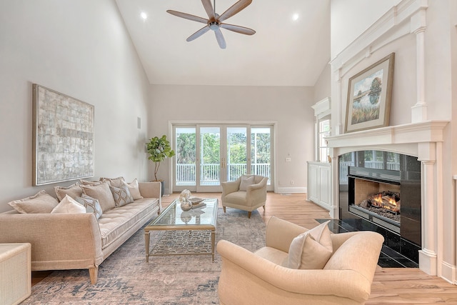 living area with ceiling fan, a high end fireplace, recessed lighting, light wood-style flooring, and high vaulted ceiling