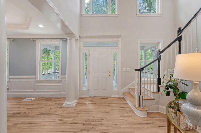 entrance foyer featuring decorative columns, stairway, visible vents, and a towering ceiling