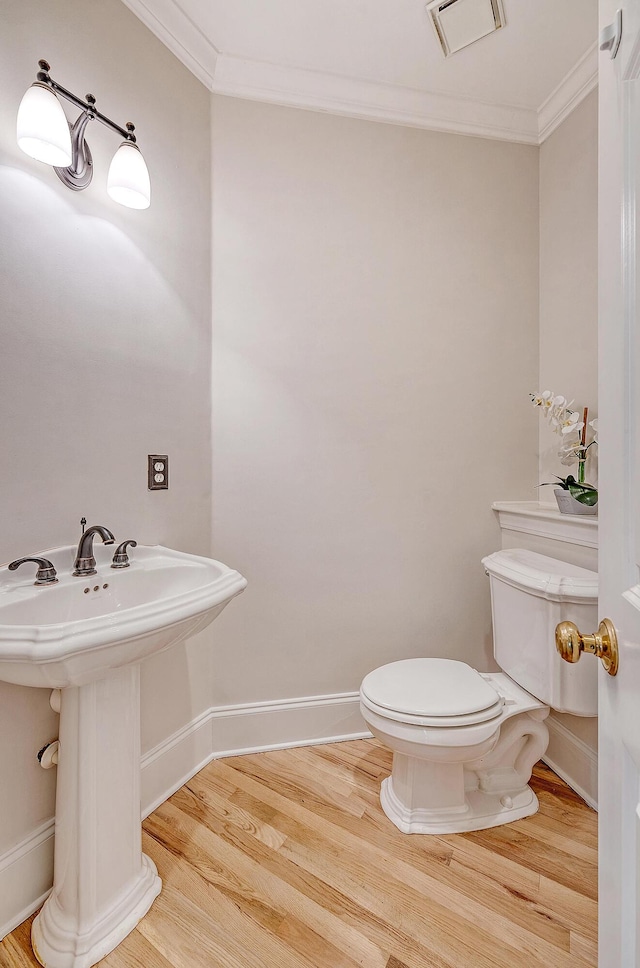 half bath with crown molding, visible vents, toilet, and wood finished floors