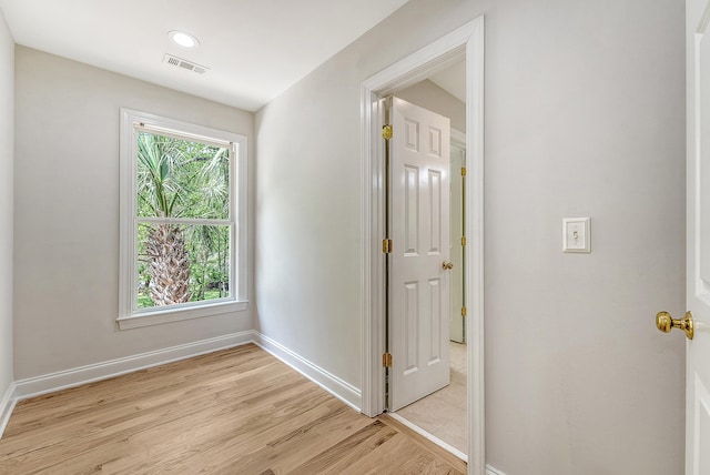 corridor with light wood-type flooring, baseboards, and visible vents