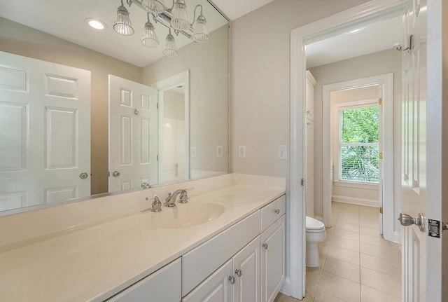 bathroom featuring baseboards, a notable chandelier, toilet, vanity, and tile patterned flooring